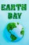 Creative concept with outline lettering Earth Day in green fresh grass sprouts and planet model on blue background. Save planet, n