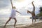 Creative couple relaxing on the ocean beach. A man and a woman do somersaults and jumps in the water. The concept of unusual