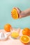 Creative and fashionable photo, pastel colors. Female hand crushes orange, juice