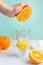 Creative and fashionable photo, pastel colors. Female hand crushes orange, juice. Vertical frame. Delicious juice and strawberry