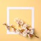 Creative flat lay composition: paper frame and blooming sakura branch on yellow background. Top view, floral frame, abstract