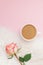Creative flat lay overhead top view coffee milk latte cup rose flower on millennial pink background copy space minimal style. Fall