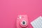 Creative flat lay photo of workspace desk with keyboard and pink fast print camera on a pink background