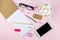 Creative flat lay photo of workspace desk with smartphone, eyeglasses, pen, pencil and notebook, minimal style on pink background.