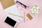 Creative flat lay photo of workspace desk with smartphone, eyeglasses, pen, pencil and notebook, minimal style on pink background.