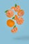 Creative food idea with fresh ripe whole and sliced mandarine flying in air isolated on a blue background