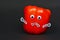 Creative food photography of red ripe paprika with funny goggle eyes, stick hands and sad mouth isolated on black background