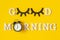 Creative good morning concept. White letters, black eyeleshes and alarm clock on yellow background. Top view, Flat lay