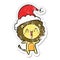 A creative happy distressed sticker cartoon of a lion wearing santa hat