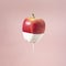 Creative healthy food concept of fruit dipped in white paint that flows down the fruit. Delicious sweet apple on pastel background