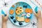 Creative idea for Halloween kids breakfast or snack. Funny monster toast with pumpkin, olive spiders and white ghost sauce.