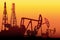 Creative illustration of oil pump industry silhouette, field pumpjack, rig drill over sunset  on background. Art design