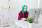 Creative, illustrator and designer concept - happy woman with green hair is drawing a project