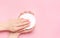 Creative image of woman moisturizing her hands with cosmetic cream with copy space on pink background in minimalistic