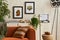 Creative interior composition of living room with designed couch, two mock up poster frames, coffee table, plants, industrial lamp