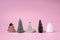 Creative layout made with miniature Christmas trees and ornaments on pink background