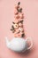 Creative layout made of whte tea pot with orange roses on pink background