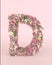 Creative letter D concept made of frash Spring wedding flowers. Flower font concept on pastel pink background