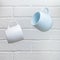 Creative levitation of two blue and white cups against the background of a kitchen stone brick wall of a milky shade, the concept