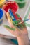 Creative little boy painting its hand with a paintbrush with col