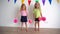 Creative little girls pretending cheerleaders holding pink pompon paper balls