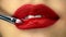 Creative makeup artist puts on a lipgloss on a model's lips
