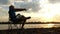 Creative Man Sits, Reads, Does an Exercise on a Riverbank at Sunset in Slo-Mo