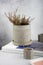 Creative Narural homemade flowerpot in gray concrete with dried flowers on a shelf in a cozy home. Wabi sabi, eco green