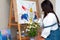 Creative pensive female painter paints a colorful abstract picture. Closeup of painting process in art workshop or home