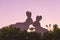 Creative photo of two silhouette paper rabbits in the chamomile flowers and green grass on the sunset sky background