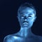 Creative portrait of surreal girl with glowing skin, blue tone in dark