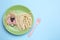 Creative serving for kids. Plate with cute dog made of tasty pasta, sausage and cucumber on light blue table, flat lay. Space for