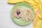 Creative serving for kids. Plate with cute dog made of tasty pasta, sausage and cucumber on white wooden table, flat lay. Space