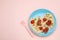 Creative serving for kids. Plate with cute octopuses made of sausages, pasta and vegetables on pink table, flat lay. Space for