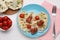 Creative serving for kids. Plate with cute octopuses made of sausages, pasta and vegetables on white wooden table, flat lay