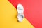 Creative shot of female white leather sandal with rhinestones and metal rivets on a bright red and yellow graphic background.