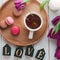 Creative spring composition with tea, macarons, purple tulipsand wooden letters