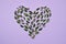 Creative Summer composition. Green leaves arranged in heart shape over violet background. Love concept. Flat lay, top view