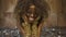 Creative surreal portrait of african american female model with gold glossy makeup surrounded by silver confetti