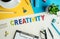 Creativity word on desk office background with supplies.