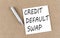 CREDIT DEFAULT SWAP text on sticky note on a cork board with pencil
