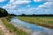 Creek through green wetlands over blue sky at the Oostervoorts Diep national park