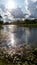 Creek in the parklands with sun peaking through the white clouds