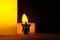 Creepy black ghost with white mask costume standing in front of candle light at night. Miniature people conceptual photography