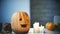 Creepy carved Halloween pumpkin smiling with flamed candles on table, traditions