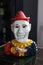 Creepy clown figurine with no eyes, holding out hand for money
