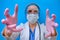 Creepy doctor`s hands reaching forward to the patient as if in delirium. Frightening nurse in medical gloves on a blue background