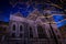 Creepy nighttime shot of an old church with tree branches in the foreground