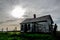 Creepy, old and aged abandoned house in a field under the cloudy and rainy sky