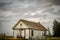 Creepy, old and aged abandoned house in a field under the cloudy and rainy sky